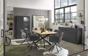 Moderner Esstisch mit Holzplatte und schwarzen Metallbeinen, umgeben von grauen Stühlen in einem stilvollen Esszimmer mit großen Fenstern und urbanem Ausblick, seitliche Perspektive.