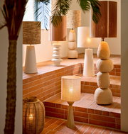 Eine stilvolle Sammlung von Lampen auf einer Treppe mit Terrakottafliesen, darunter ein Lampenfuß mit mehreren runden Elementen, aufgenommen aus einer seitlichen Perspektive.