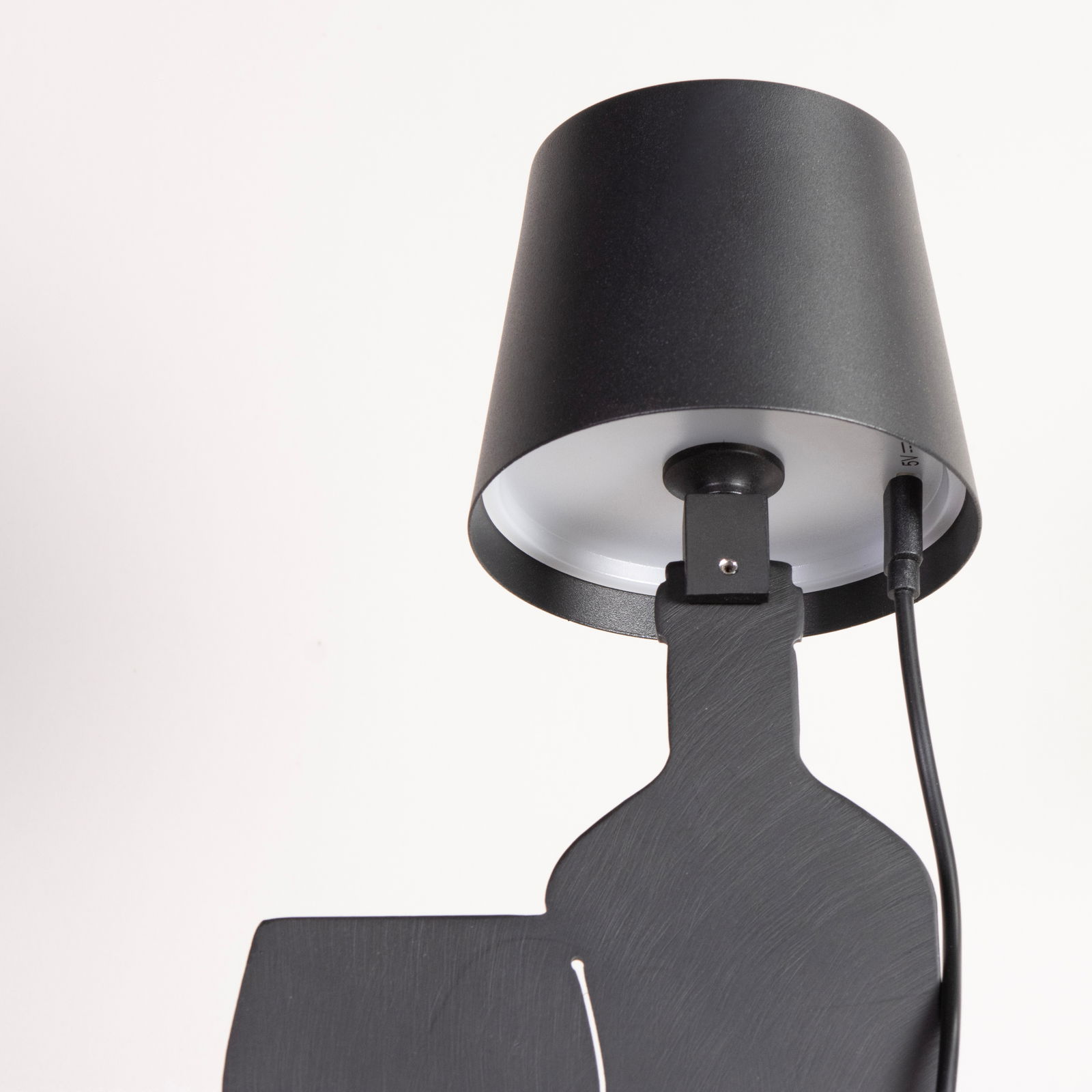 Schwarze Akku-Tischleuchte aus seitlicher Perspektive mit Kabelanschluss