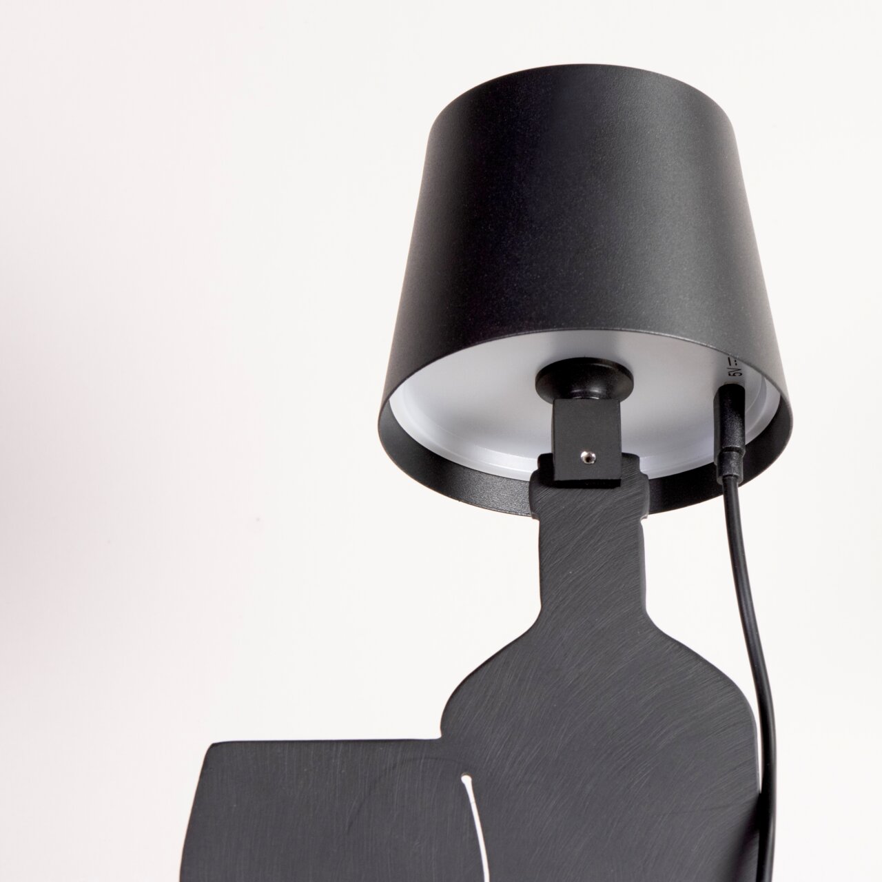 Schwarze Akku-Tischleuchte aus seitlicher Perspektive mit Kabelanschluss