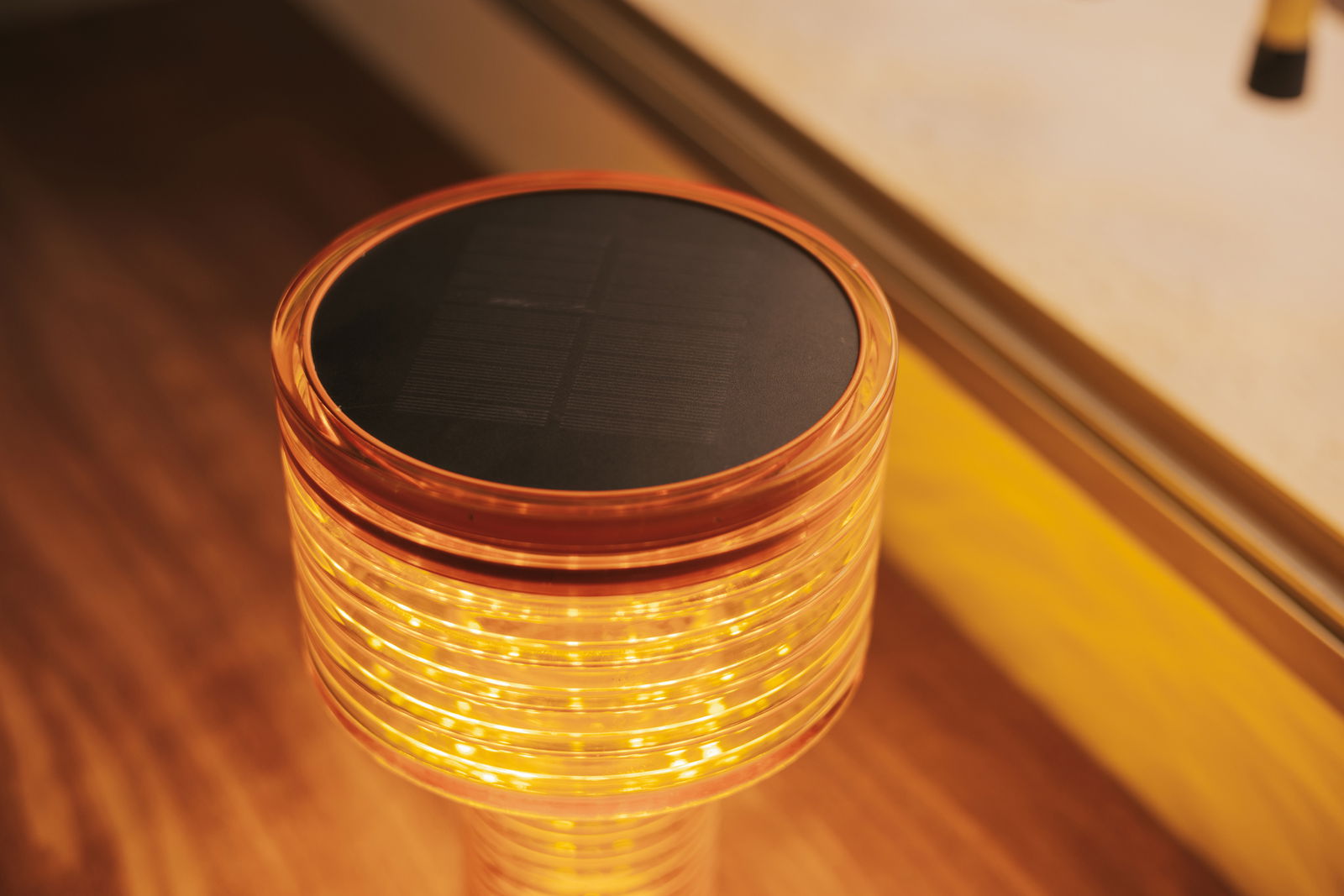 Nahaufnahme einer Akku-Solar-Tischleuchte mit leuchtendem, spiralförmigem Design und Solarpanel auf der Oberseite.