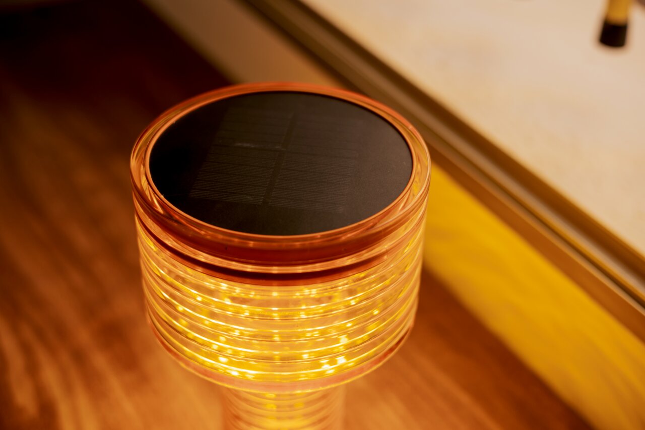 Nahaufnahme einer Akku-Solar-Tischleuchte mit leuchtendem, spiralförmigem Design und Solarpanel auf der Oberseite.