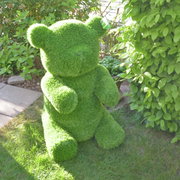 Grüner Bär aus Kunstrasen, frontal im Garten platziert