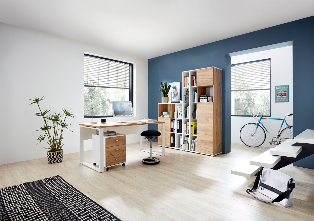Moderner Büroraum mit Schreibtisch, Rollcontainer und Aktenschrank in Holzoptik, seitliche Perspektive.