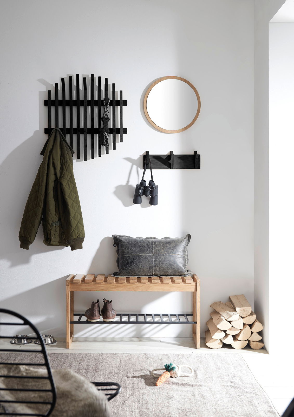 Linea Natura Garderobenpaneel BANTRY Garderobenbank aus Holz mit schwarzem Metallregal, dekoriert mit Kissen, in einem modernen Flur mit Spiegel und Hakenleiste, seitliche Perspektive