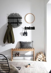 Garderobenbank aus Holz mit schwarzem Metallregal, dekoriert mit Kissen, in einem modernen Flur mit Spiegel und Hakenleiste, seitliche Perspektive