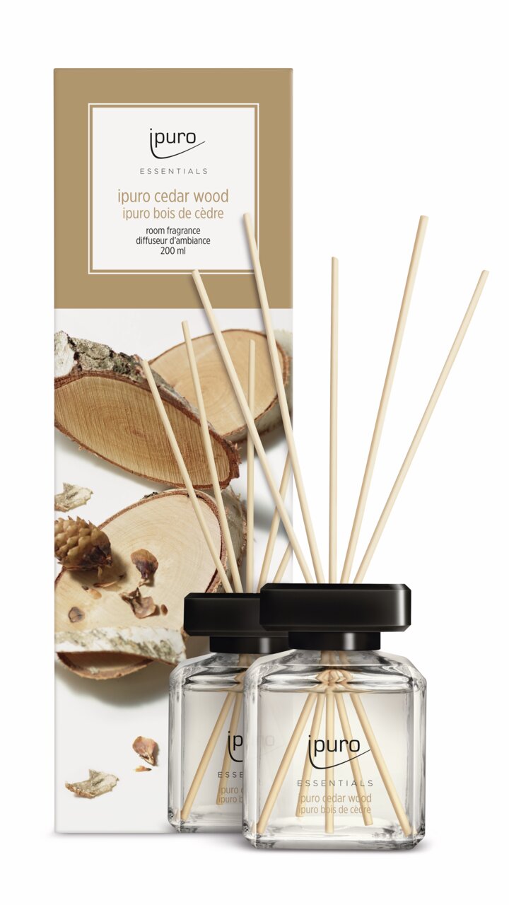 Cedar Wood kamerparfum 200 ml met twee glazen flesjes en geurstokjes, afgebeeld op de voorkant van de verpakking.