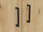 Nahaufnahme von zwei schwarzen Griffen auf einer Holzoberfläche, perspektivisch von vorne betrachtet.