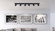 Moderne plafondspots met zes verstelbare lampen in een woonkamer, gezien vanaf de zijkant.