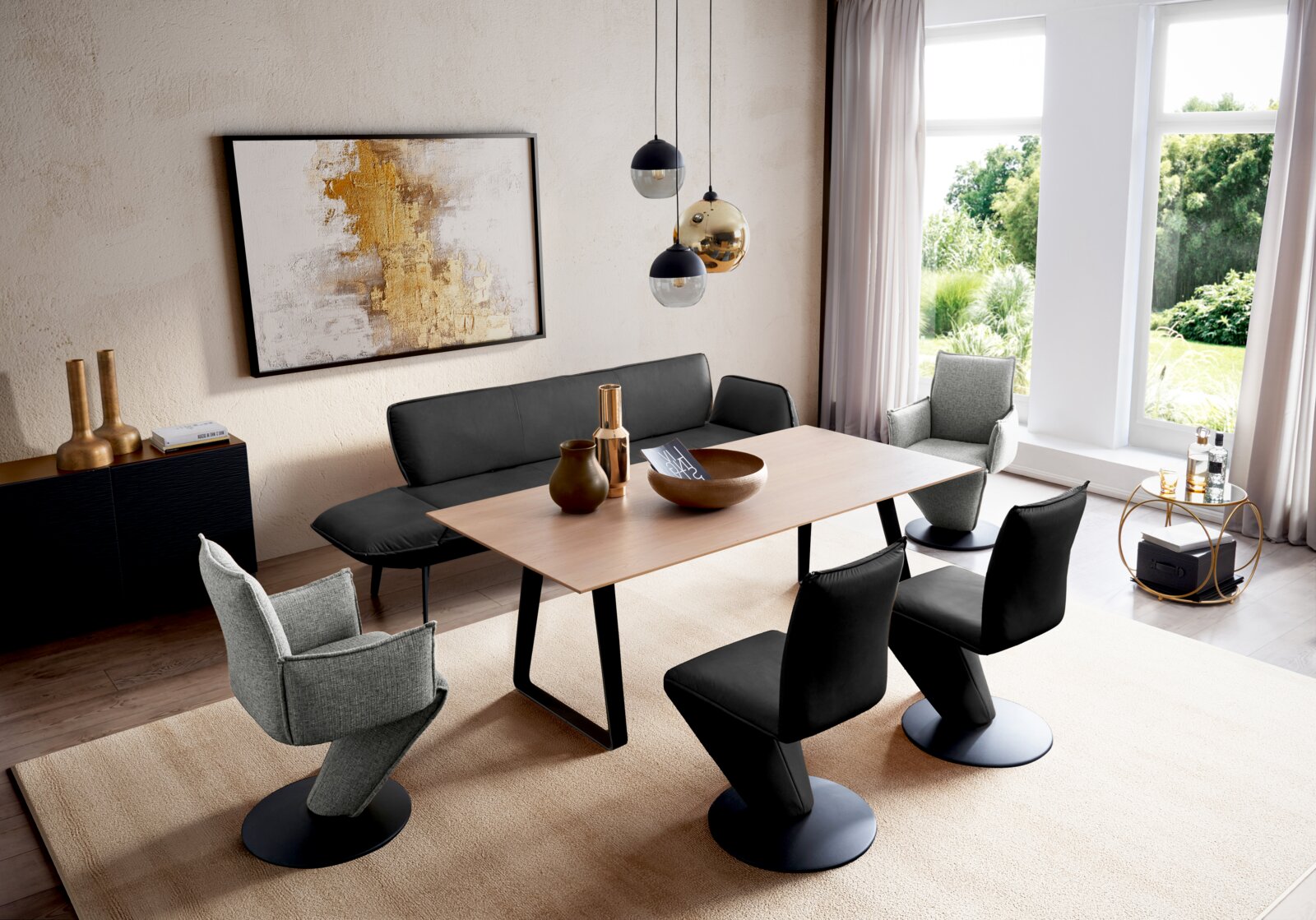 Modernes Esszimmer mit hellem Holztisch, schwarzen Stühlen und grauen Sesseln, Pendelleuchten und großer Fensterfront; Perspektive: leicht erhöhte, schräge Ansicht von vorne links.