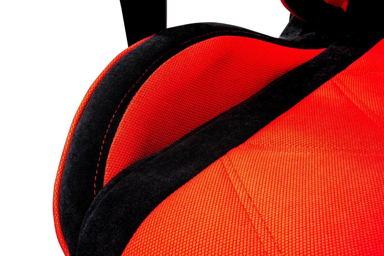 Close-up van een gamingstoel met rode bekleding en zwarte accenten, gezien vanaf de zijkant.