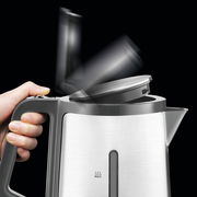 Moderner Wasserkocher mit Edelstahlgehäuse, geöffneter Deckel in Bewegung, seitliche Ansicht.