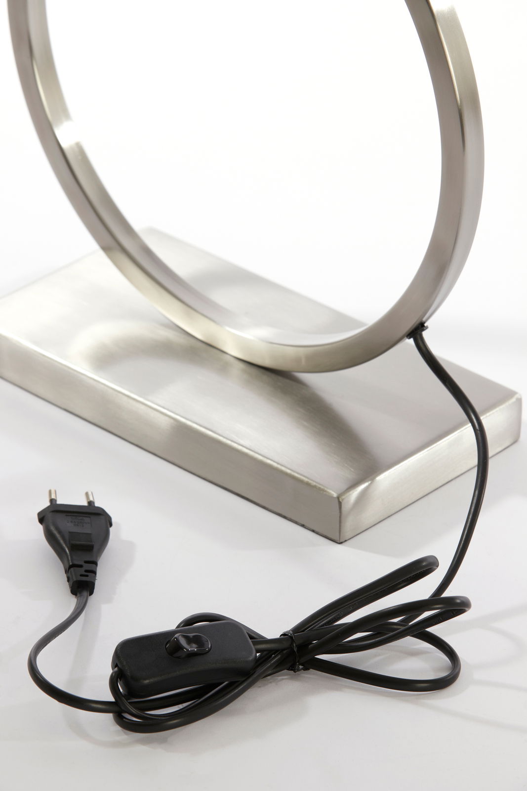Nahaufnahme eines modernen Lampenfußes aus Metall mit rundem Design, Kabel und Schalter sichtbar, seitliche Perspektive