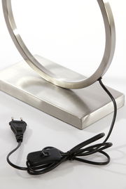 Nahaufnahme eines modernen Lampenfußes aus Metall mit rundem Design, Kabel und Schalter sichtbar, seitliche Perspektive