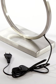 Nahaufnahme eines modernen Lampenfußes aus Metall mit rundem Design, Kabel und Schalter sichtbar, seitliche Perspektive