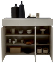 Frontale Ansicht einer breiten Kommode mit offenen Türen, gefüllt mit Geschirr und Dekorationsgegenständen auf der Oberseite.