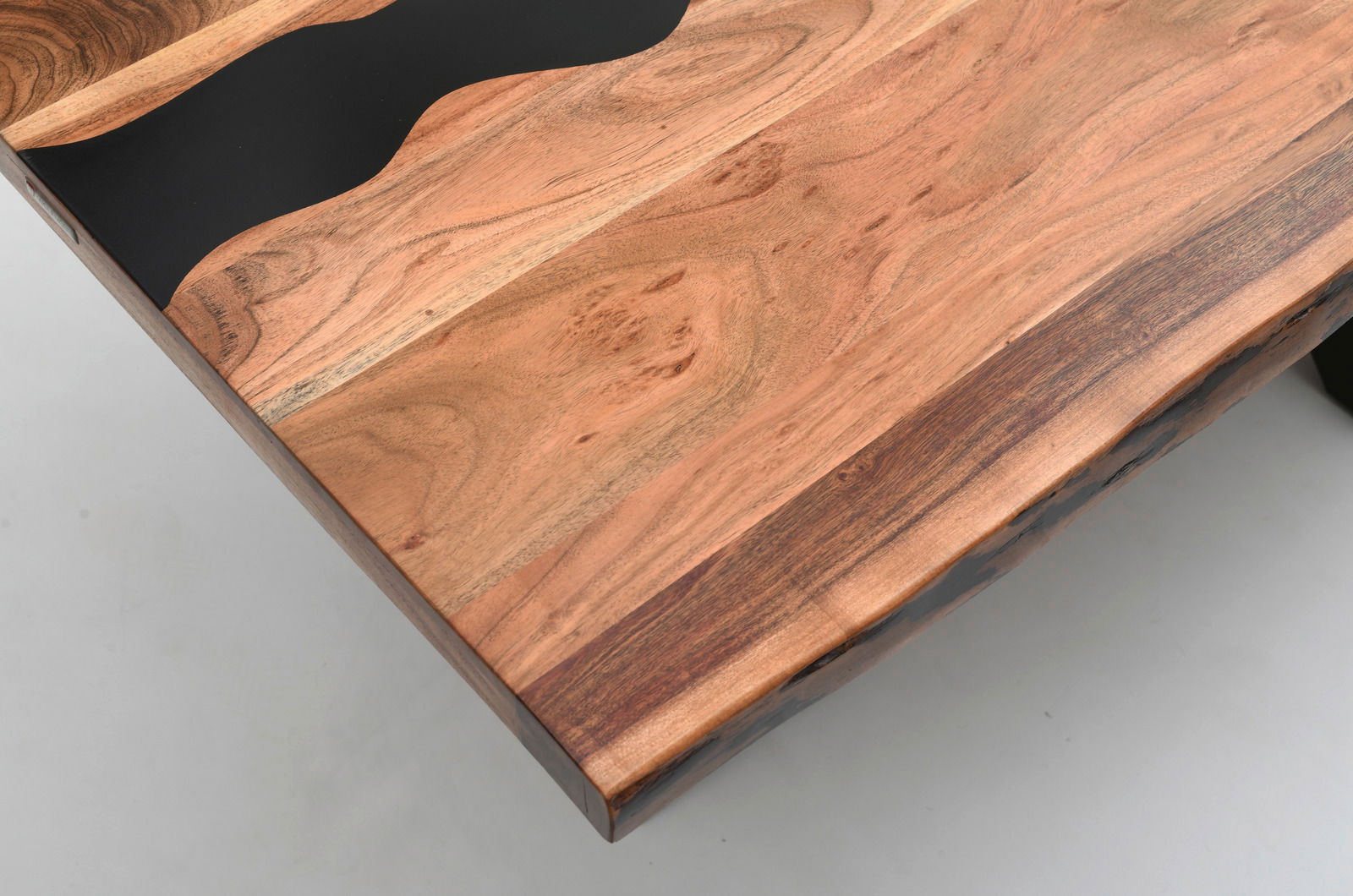 Nahaufnahme eines Esstisches mit einer Tischplatte aus gemasertem Holz und schwarzen Akzenten, von oben fotografiert.