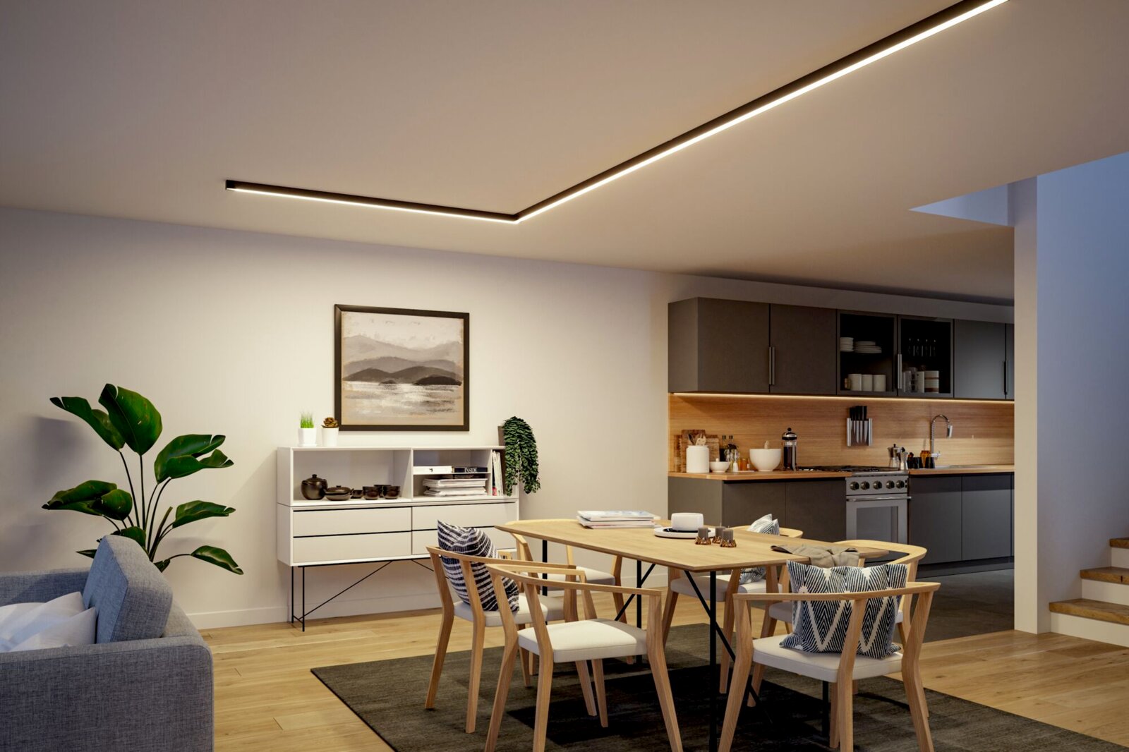 Modernes Wohn- und Esszimmer mit integrierter Küche, warmweißer LED-Deckenlinienleuchte, Holztisch und Stühlen sowie grauen Küchenfronten, aufgenommen aus leicht erhöhter Weitwinkelperspektive schräg von vorn.