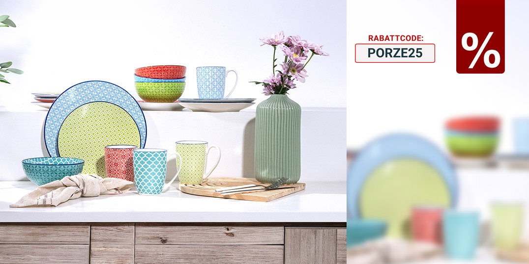 Bunt gemischtes Geschirr mit Tassen, Schalen und Vase auf heller Küchenanrichte.