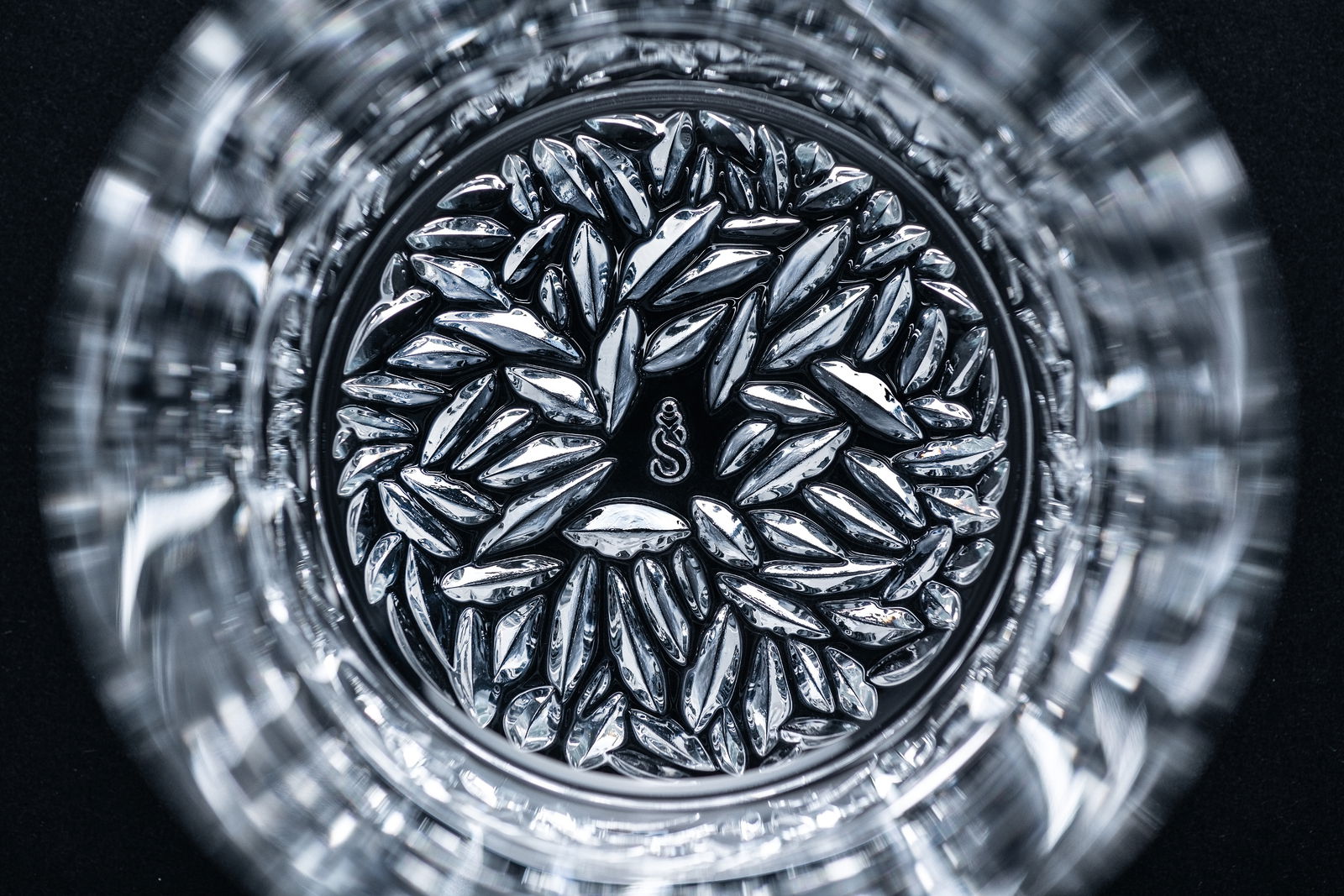 Detailansicht eines Bechers mit kunstvollem, glänzendem Muster im Boden, von oben betrachtet.