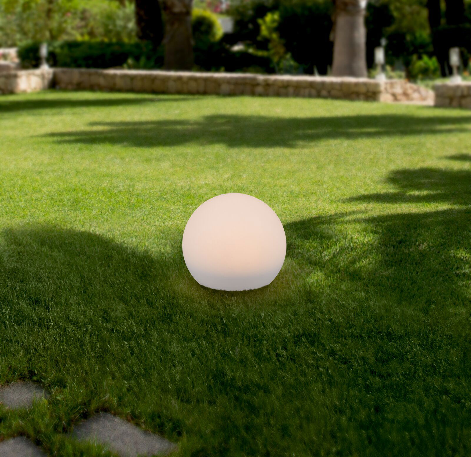 Kugelförmige Solarleuchte auf einer Rasenfläche im Garten, seitliche Perspektive