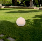 Kugelförmige Solarleuchte auf einer Rasenfläche im Garten, seitliche Perspektive