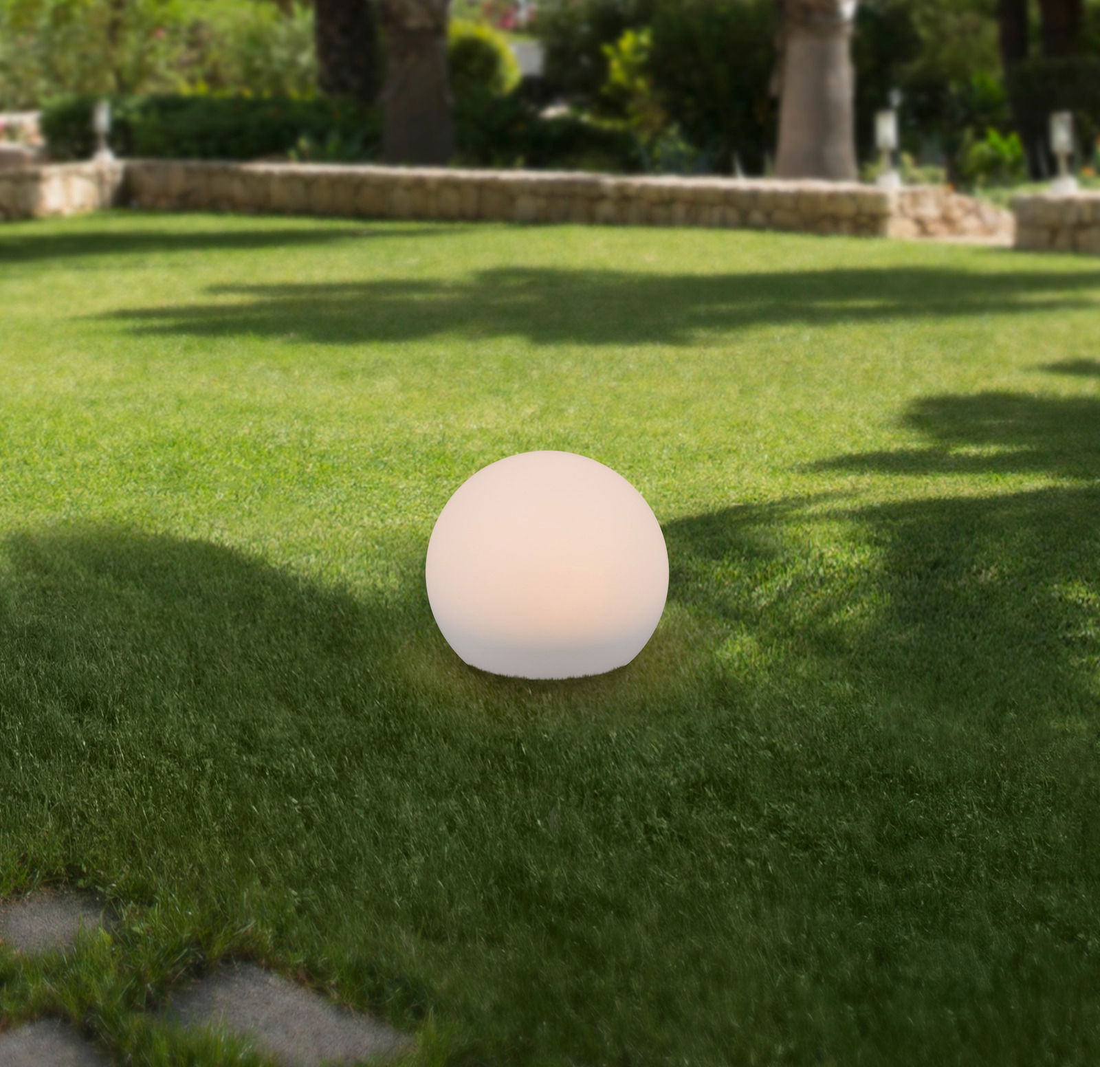 Kugelförmige Solarleuchte auf einer Rasenfläche im Garten, seitliche Perspektive