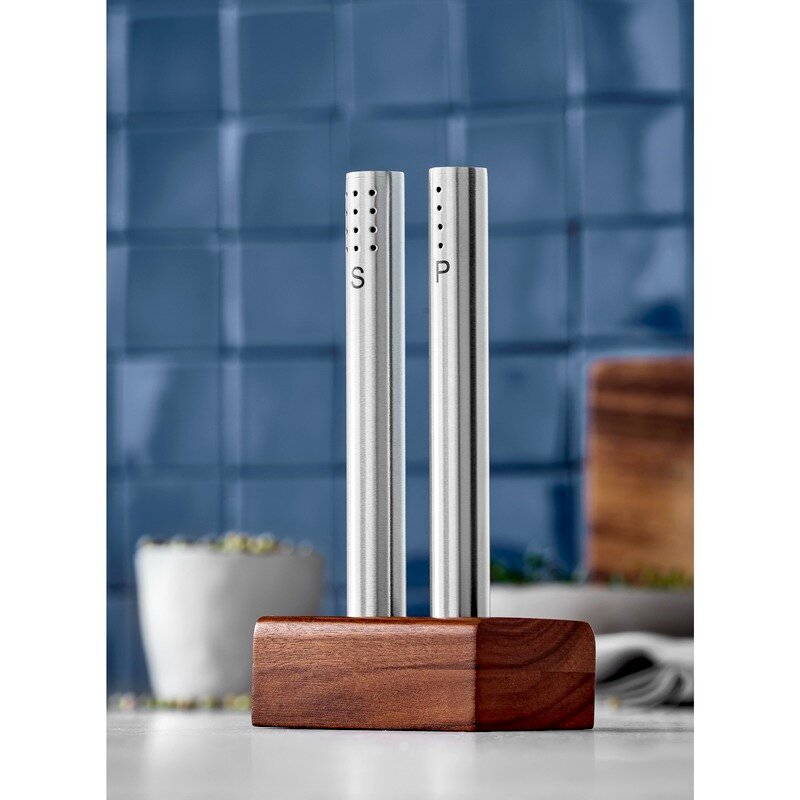 Modernes Salz- und Pfeffer-Set aus Edelstahl mit Holzständer, frontal abgebildet vor einer blauen Kachelwand.