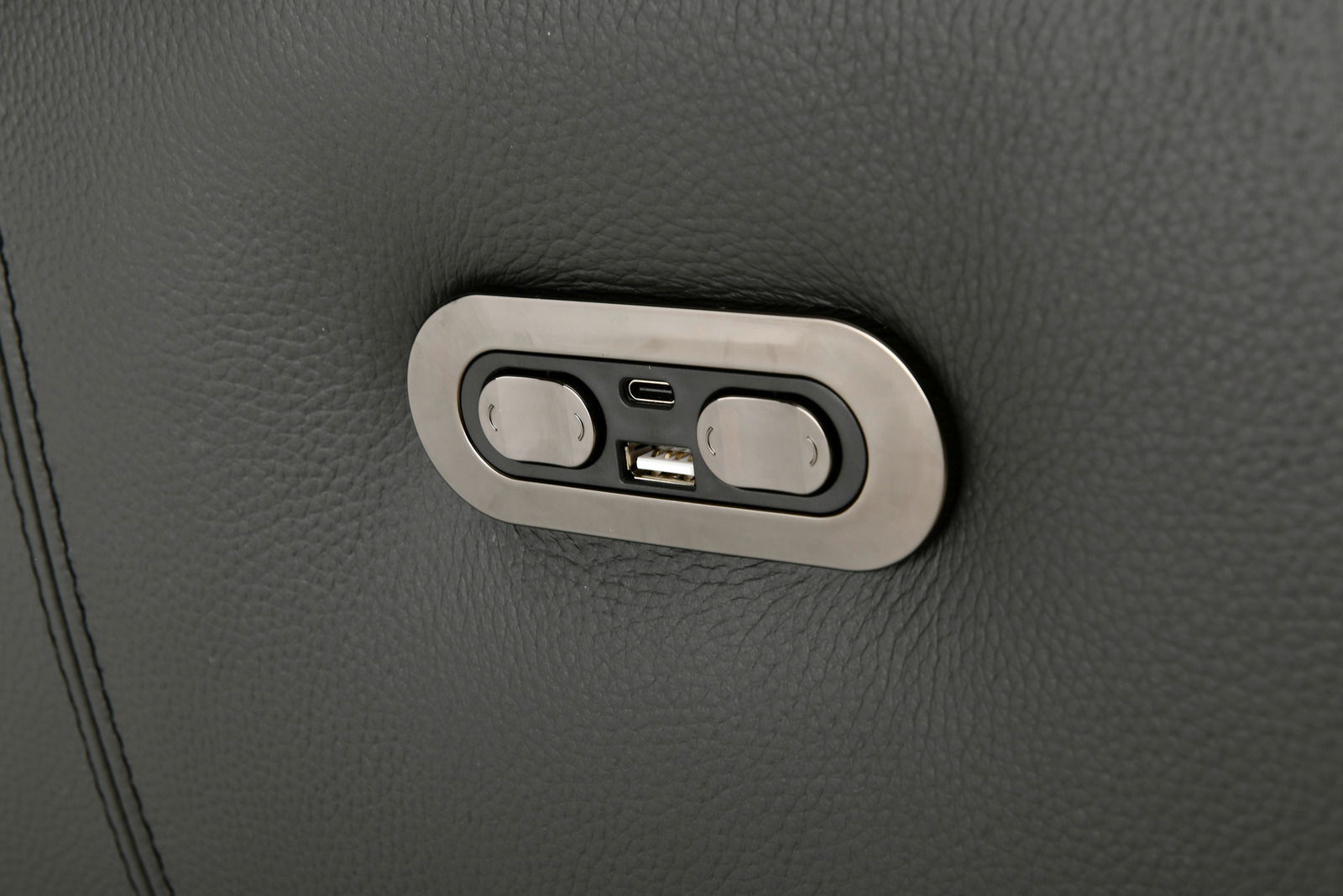 Nahaufnahme eines USB-Anschlusses und zweier Knöpfe auf einer dunkelgrauen Polstergarnitur.