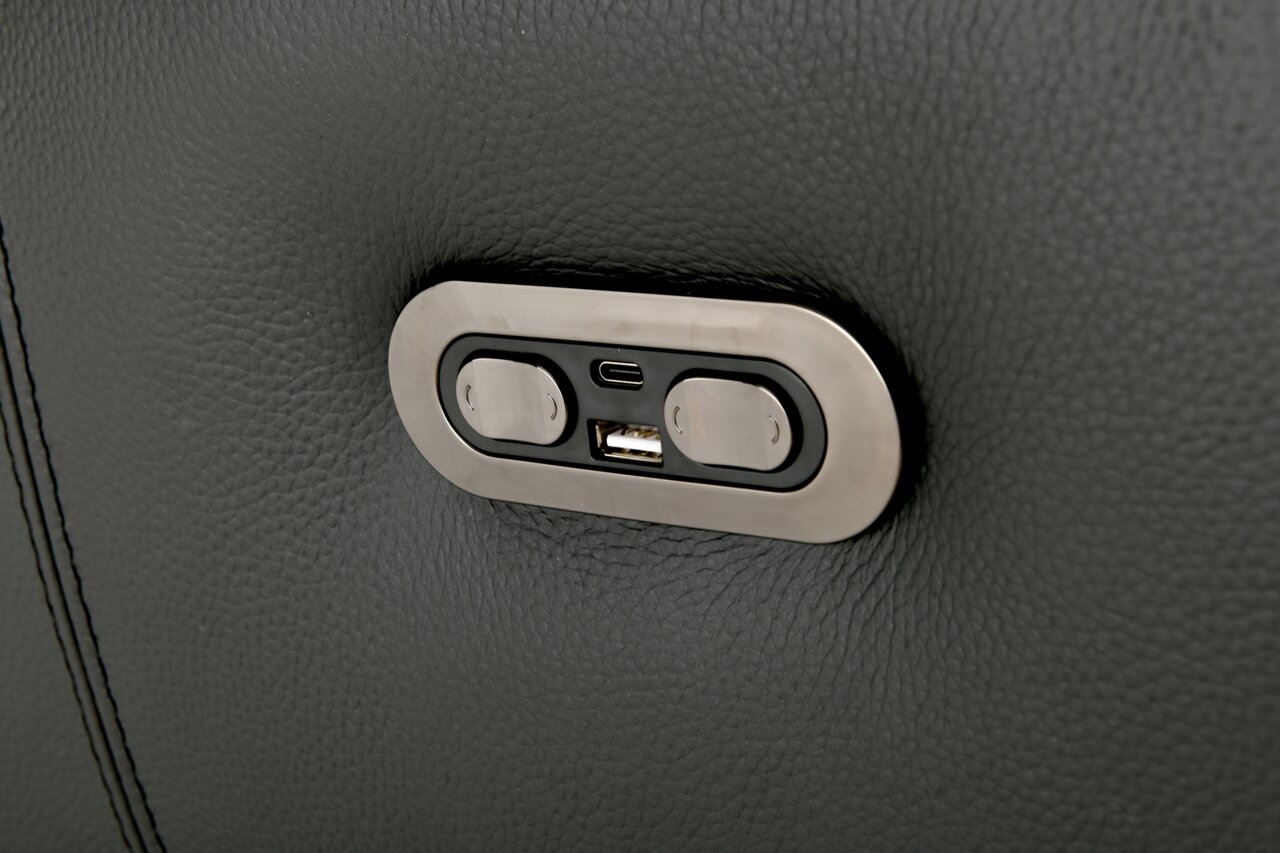 Nahaufnahme eines USB-Anschlusses und zweier Knöpfe auf einer dunkelgrauen Polstergarnitur.