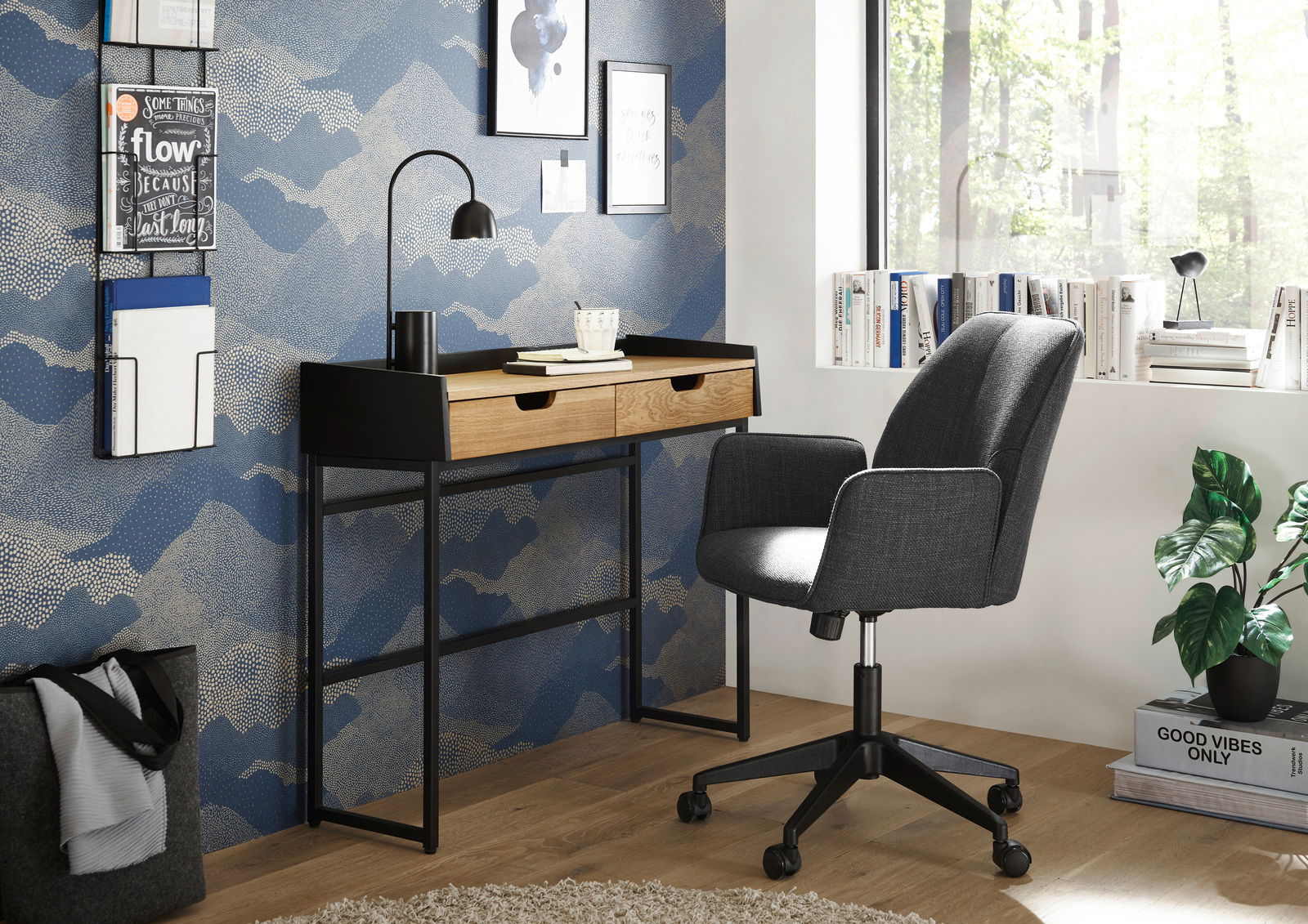 Moderner Schreibtisch mit zwei Schubladen aus Holz und schwarzem Metallgestell, seitliche Perspektive, mit grauem Bürostuhl und dekorativer Wand im Hintergrund.
