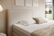 Boxspringbett mit gestepptem Kopfteil in einem modernen Schlafzimmer, seitliche Perspektive
