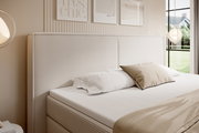 Boxspringbett mit gestepptem Kopfteil in einem modernen Schlafzimmer, seitliche Perspektive