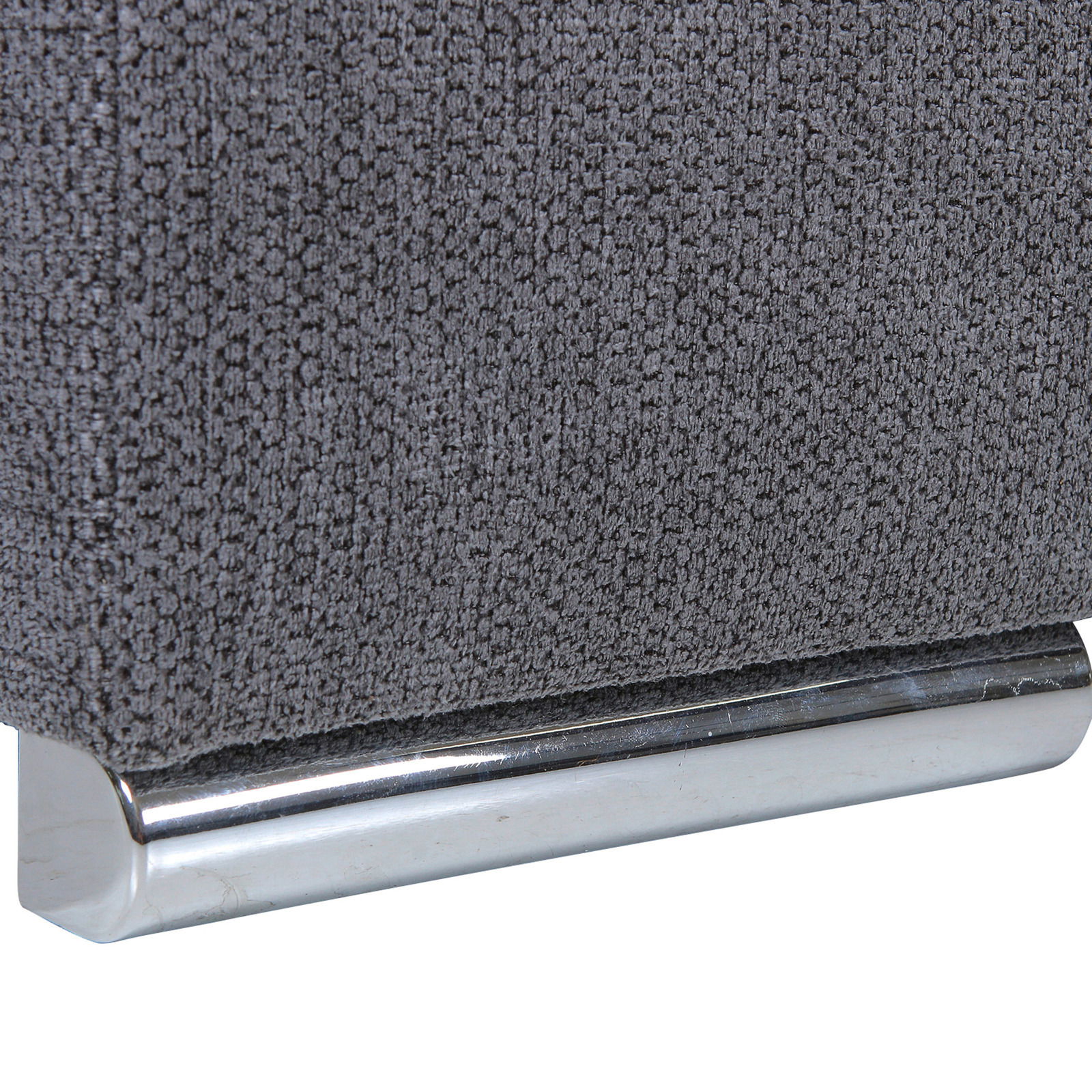 Nahaufnahme einer grauen, texturierten Stoffoberfläche mit einem glänzenden, metallischen Sockel.