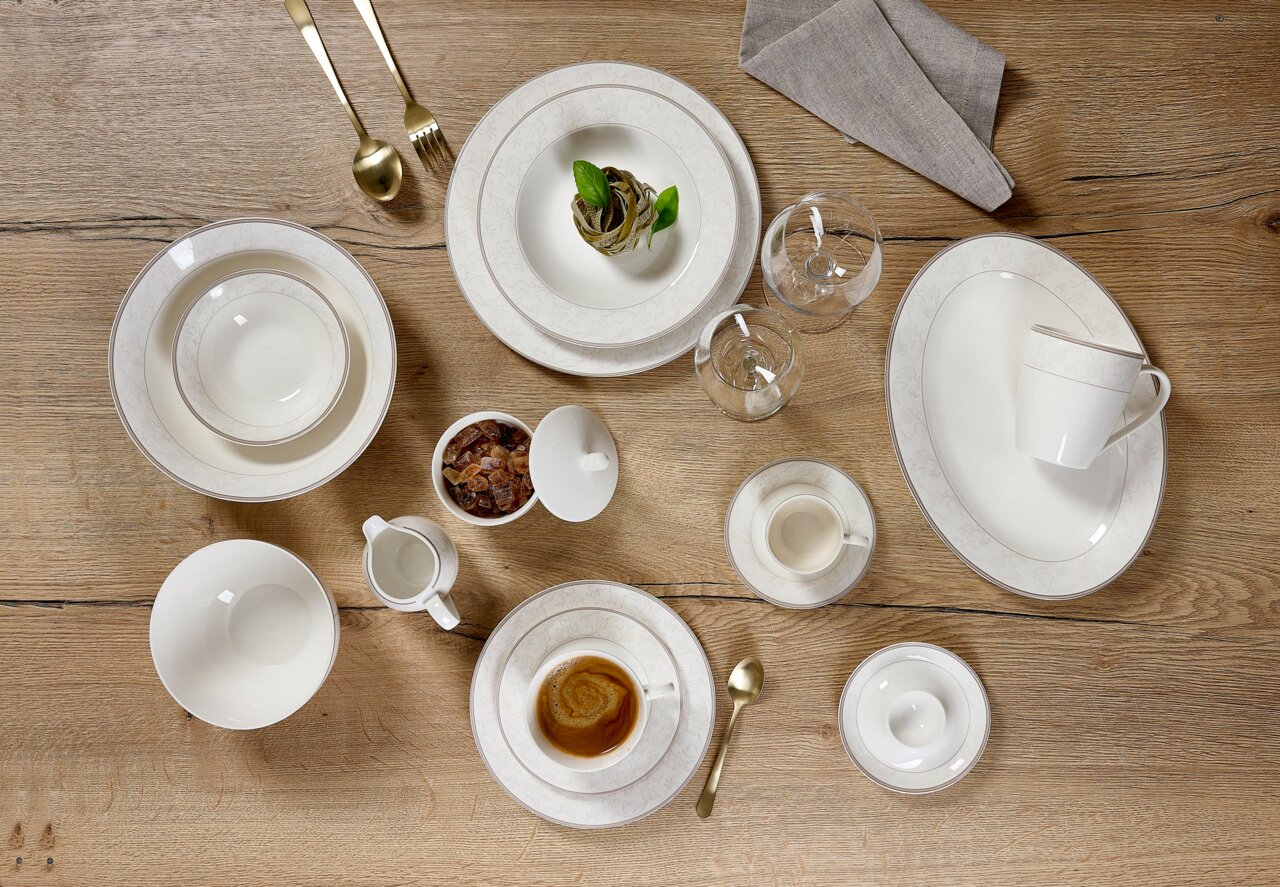 Elegante mueslischaal Isabella 15 cm van porselein, gefotografeerd van bovenaf, omringd door bijpassend servies op een houten tafel.