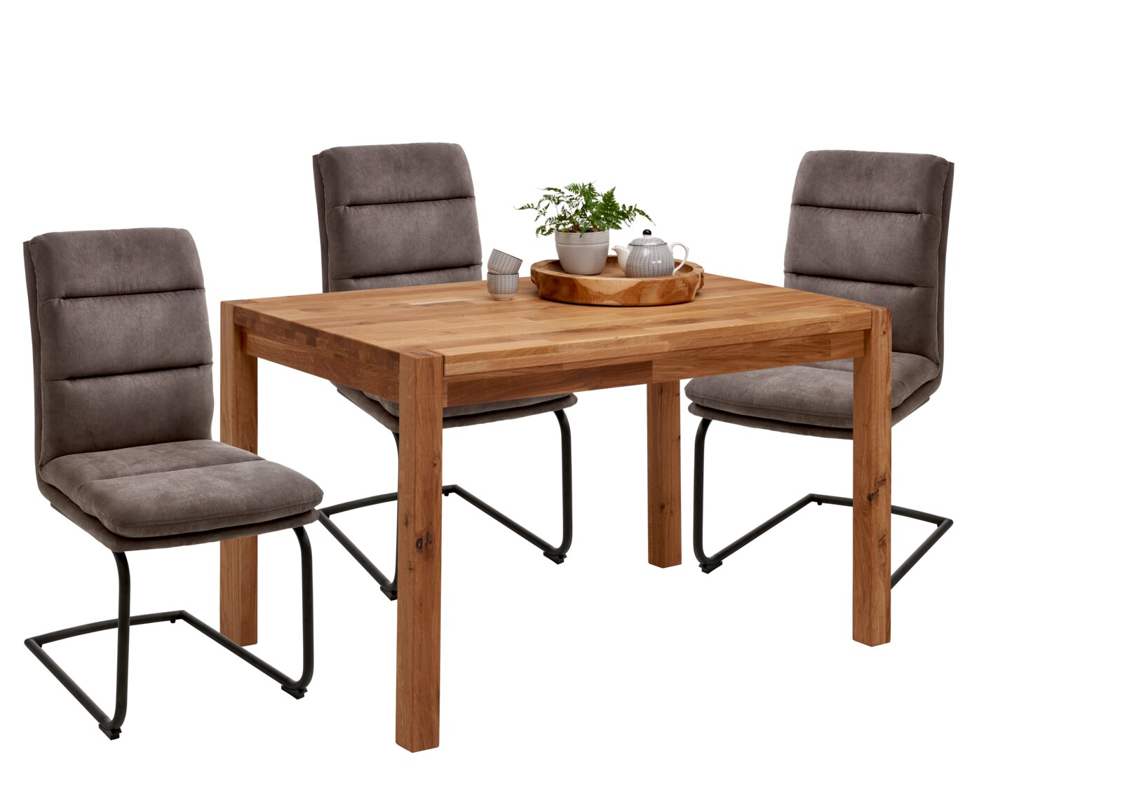 Holz-Esstisch mit drei gepolsterten Freischwinger-Stühlen in Grau und schwarzem Metallgestell, dekoriert mit Tablett, Pflanze und Teekanne, Ansicht schräg von vorne