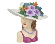Dekorative Damenbüste als Figur mit breitem weißem Hut und farbenfrohem Blumenarrangement (lila Blüten, grüne Blätter, orange Akzente), in schräger Frontansicht von links vor weißem Hintergrund.