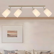 Witte plafondlamp met vier verstelbare cilindervormige spots op een rechthoekige balk, gezien van onderen in een woonkamer