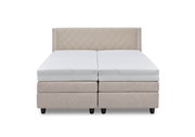 Frontansicht eines eleganten Boxspringbetts mit beigem, gestepptem Kopfteil und weißen Matratzen.