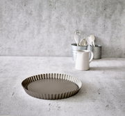 Obstbodenform Ø 30 cm aus Metall, seitliche Perspektive auf einer Küchenarbeitsplatte, im Hintergrund Küchengeräte.