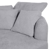 Graues Sofa mit Ottomane rechts, Nahaufnahme der Kissen und Armlehne aus seitlicher Perspektive