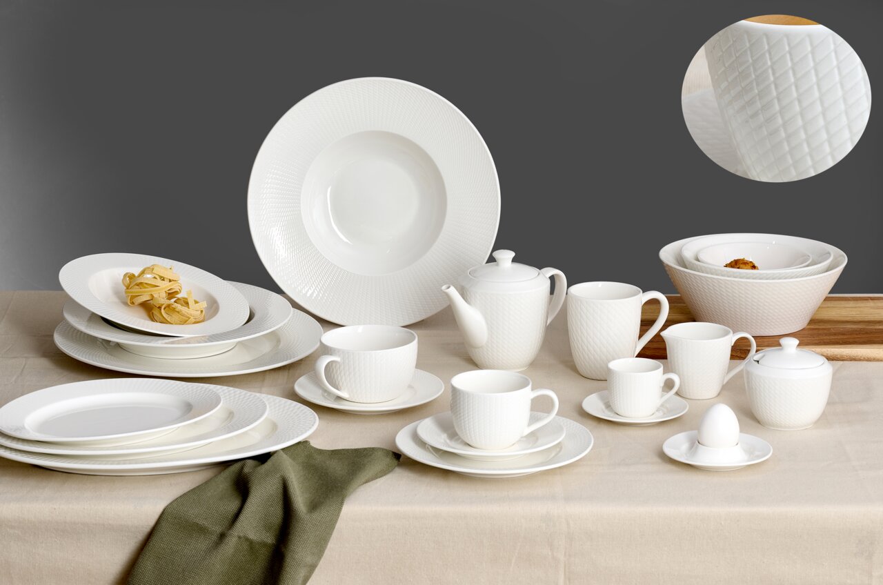Ritzenhoff & Breker Tafelset 12-tlg. SAPHIR Elegantes 12-teiliges Tafelset aus weißem Porzellan mit feinem Rautenmuster, bestehend aus Tellern, Tassen, Kannen und Schalen, auf einem Tisch von vorne präsentiert.