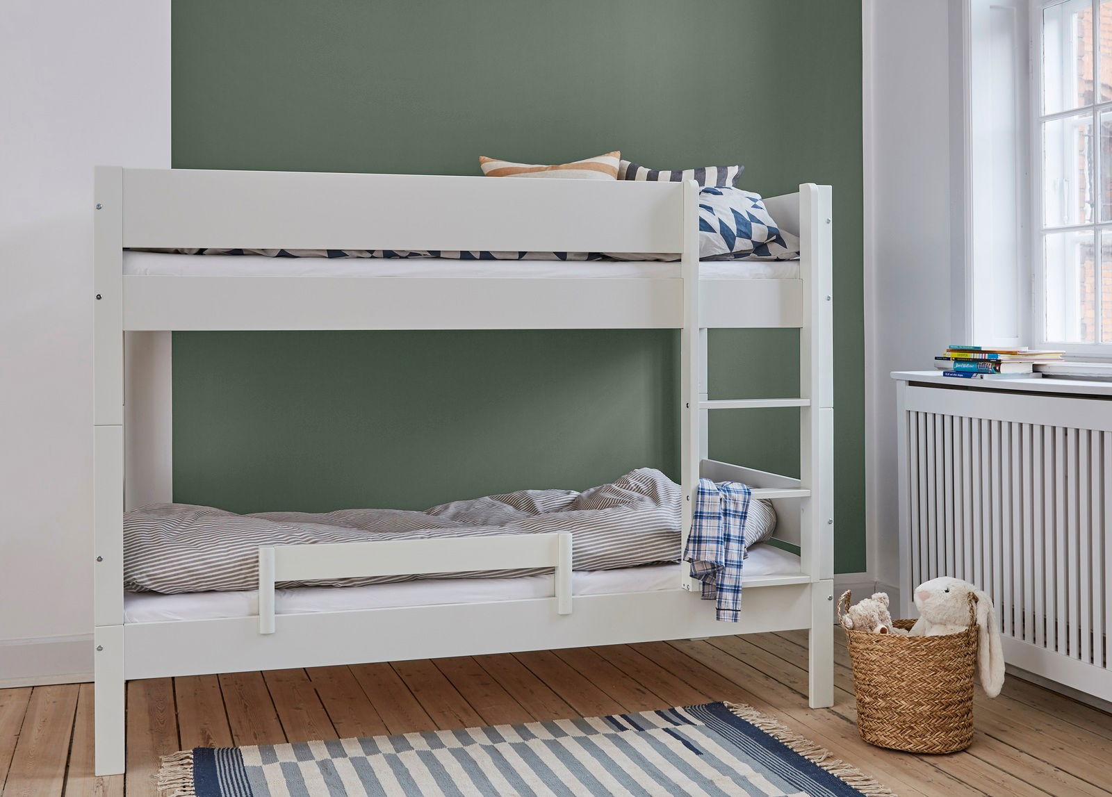 Etagenbett mit weißem Rahmen und Absturzsicherung, seitliche Leiter, Ansicht von vorne, Kinderzimmer mit grünem Hintergrund.