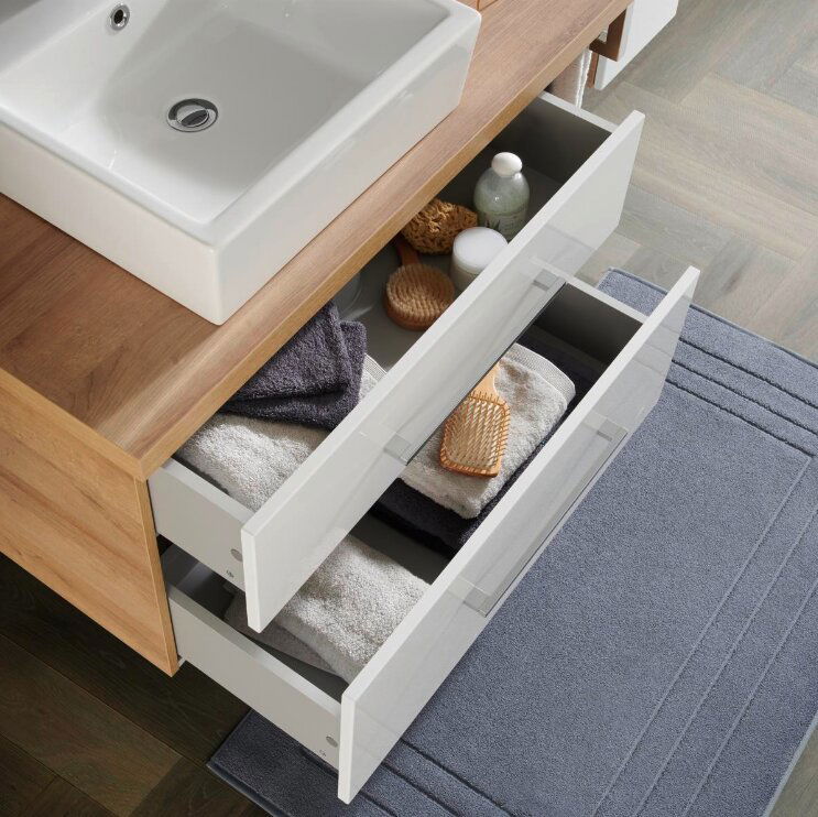 Voleo Badkombination LARA Badezimmerkombination mit Waschbecken und zwei geöffneten Schubladen, gefüllt mit Handtüchern und Pflegeprodukten, aus der Vogelperspektive.