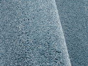 Nahaufnahme eines blauen Uni-Teppichs mit weicher, flauschiger Textur, seitliche Perspektive
