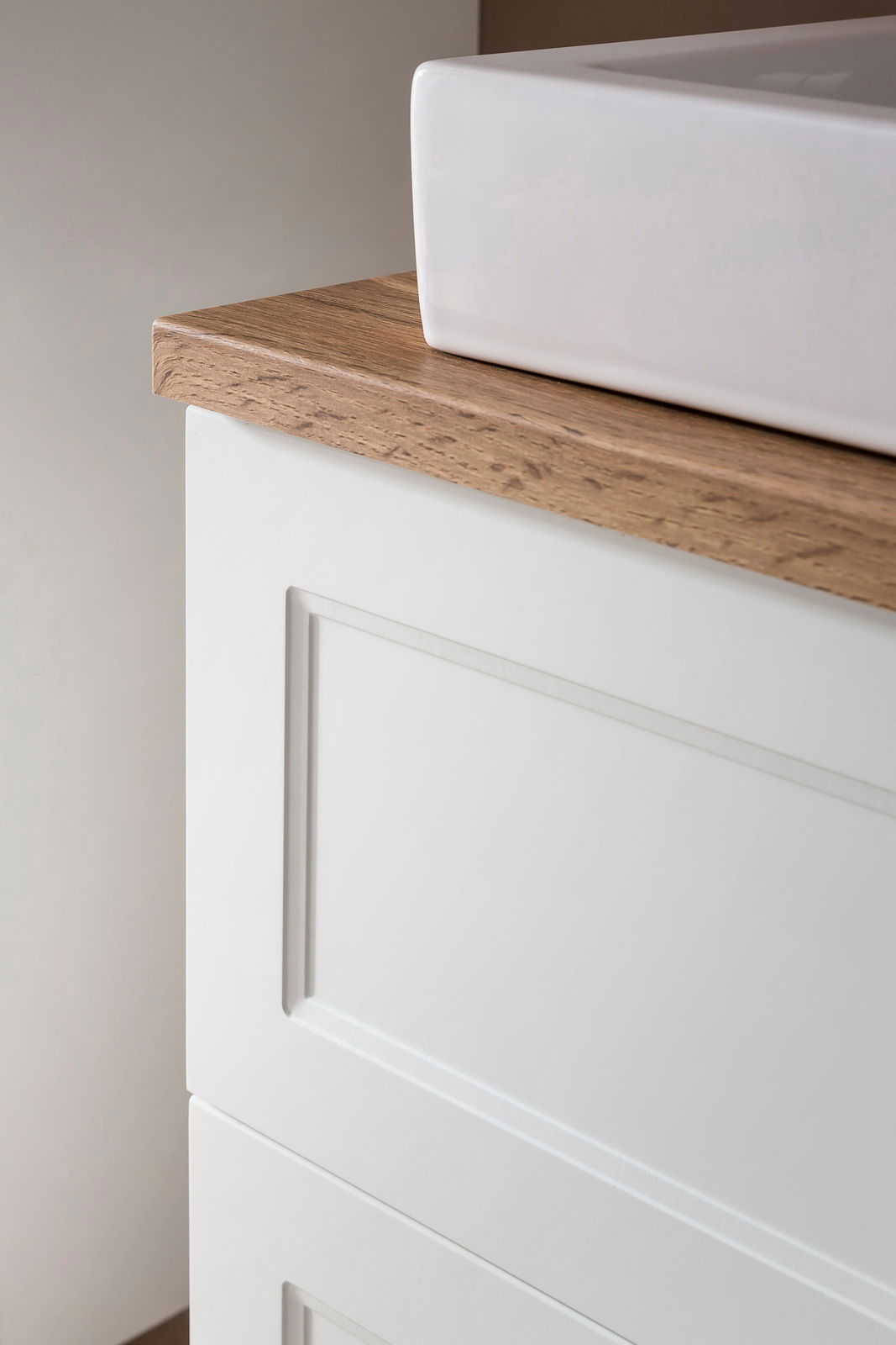 Nahaufnahme eines Waschtisch-Sets mit weißem Waschbecken und Holzarbeitsplatte, seitliche Perspektive