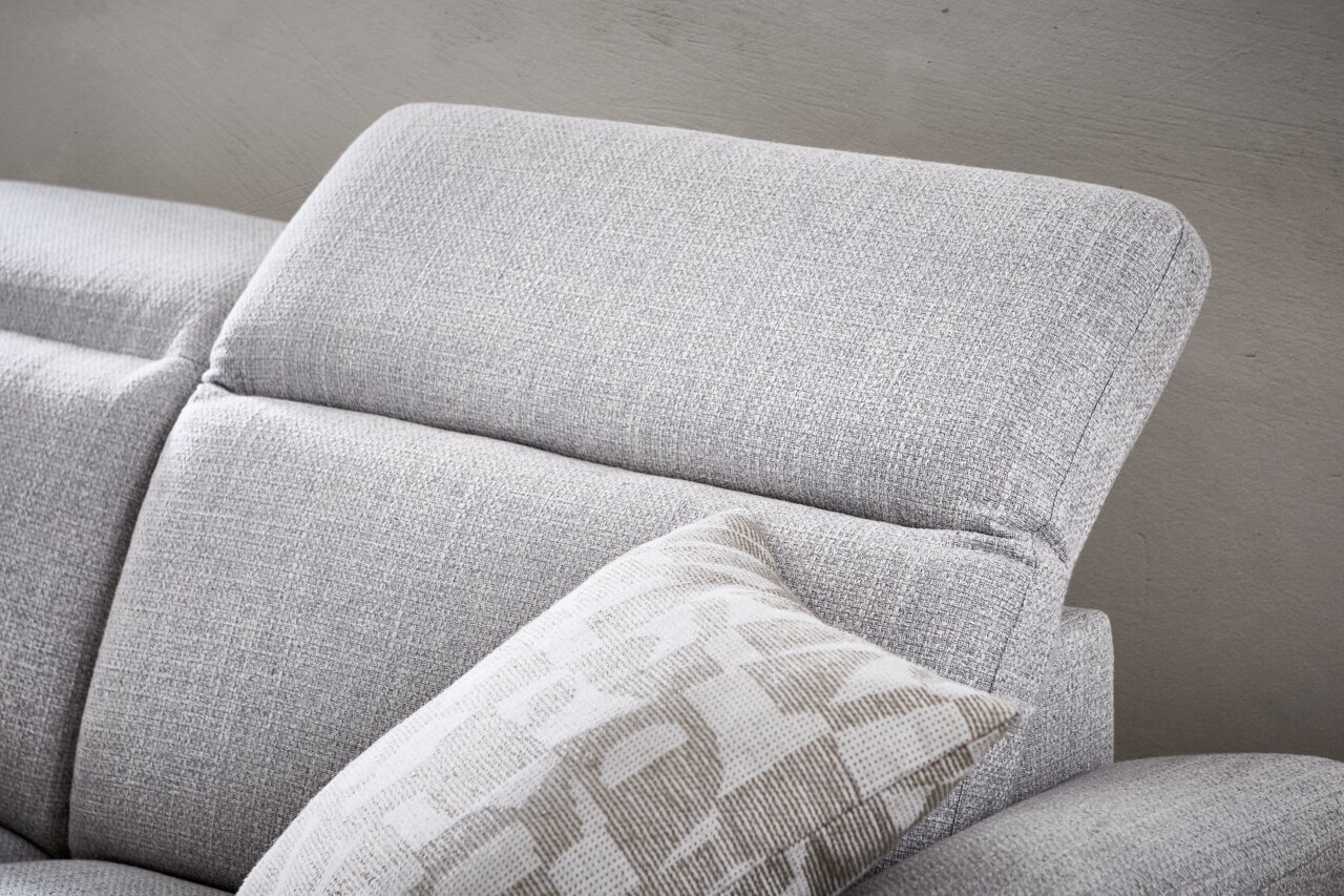Nahaufnahme eines grauen Longchairs mit verstellbarer Kopfstütze und dekorativem Kissen, seitliche Perspektive.