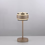 Moderne Akku-Tischleuchte in seitlicher Perspektive mit rundem, zweifarbigem Lampenschirm und schlankem Standfuß auf einem Tisch.