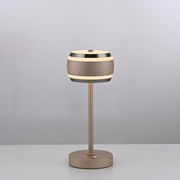 Moderne Akku-Tischleuchte in seitlicher Perspektive mit rundem, zweifarbigem Lampenschirm und schlankem Standfuß auf einem Tisch.