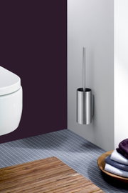 Wandmontierte WC-Bürstengarnitur aus gebürstetem Edelstahl mit zylindrischem Behälter und Griff, seitliche Frontansicht im Badezimmer neben einem weißen WC
